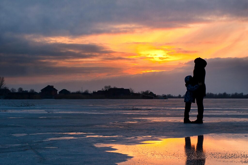 A serene sunset scene of a family silhouette on a frozen lake in Kherson, Ukraine.