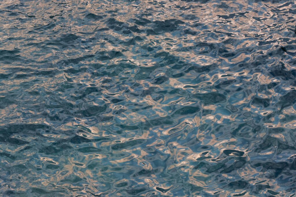 A detailed view of a rippling water surface reflecting sunset colors, creating an abstract look.