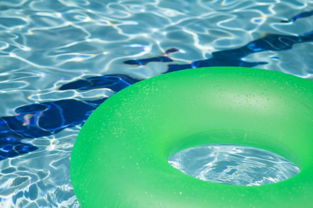 A vibrant green inflatable swim ring floating in a refreshing blue swimming pool.
